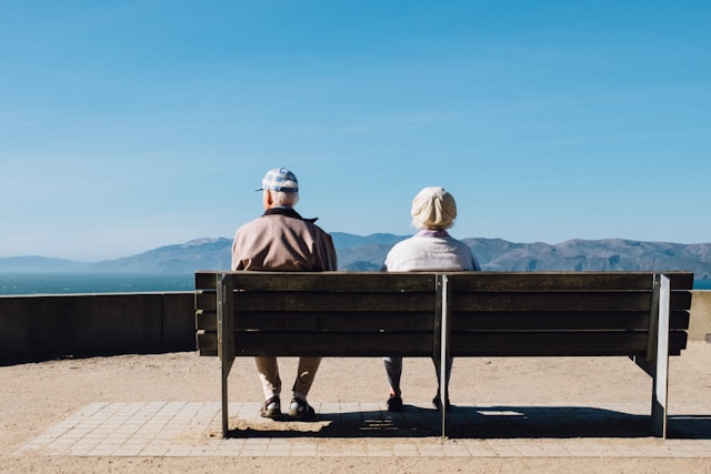 Elderly couple sitting on a bench looking at the mountains