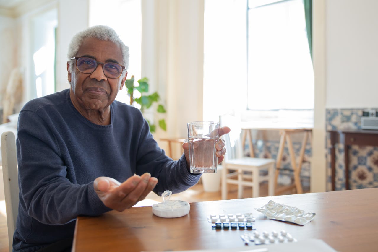 Man taking medication while sitting at his kitchen table