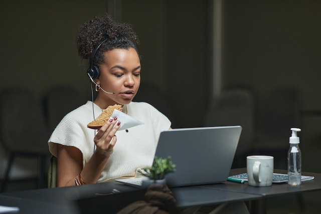 A woman eating a sandwich at her laptop